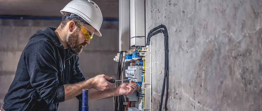 Professional electrical technician performing home electrical repairs and safety inspections in a residential property